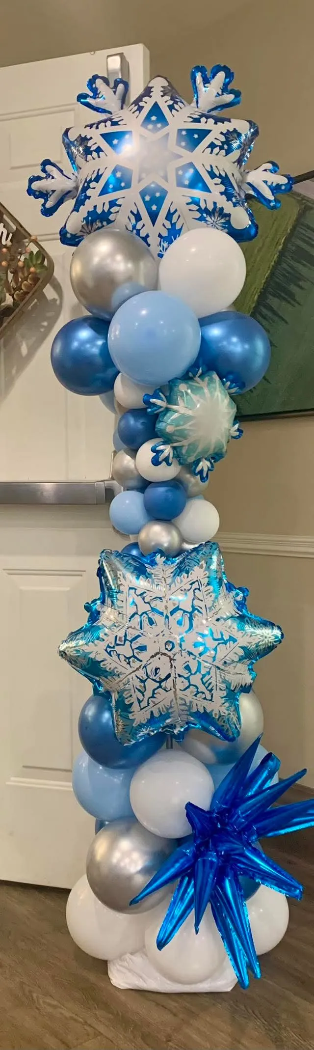 Blue, white and silver balloon column topped with snowflake balloons